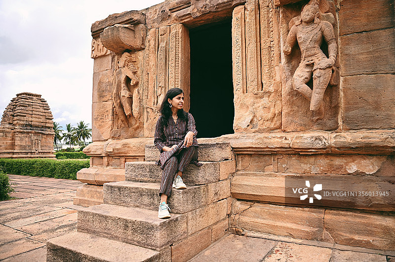 坐在印度卡纳塔克邦帕塔达卡尔古老石庙台阶上的女人图片素材