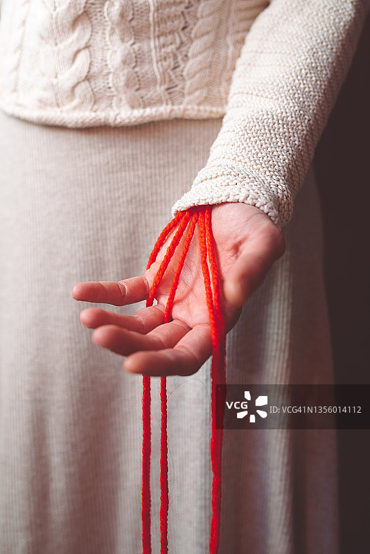 从女人手中伸出红色羊毛线，如血迹般的竖版照片图片素材