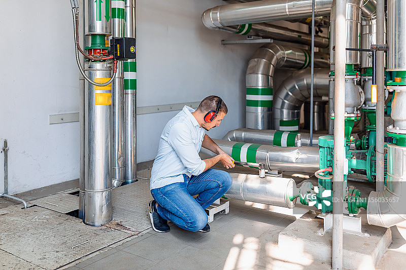 年轻技术员正在检查锅炉房的供暖系统图片素材