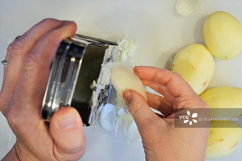 用金属刨丝器刨生土豆的女人图片素材