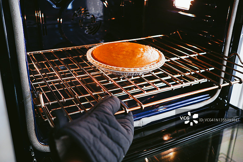 女人从烤箱里取出南瓜派图片素材