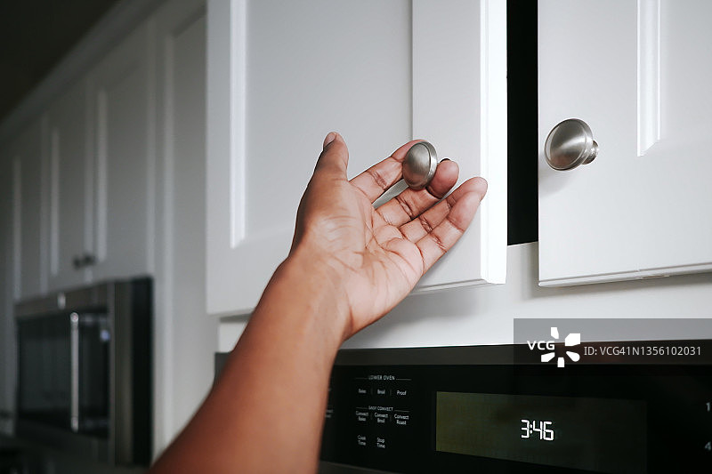 手放在厨房橱柜门把手上的女人图片素材