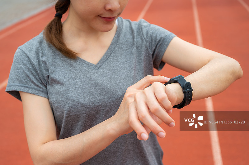 跑步者在跑步时查看智能手表上的健康状况和健身进度图片素材