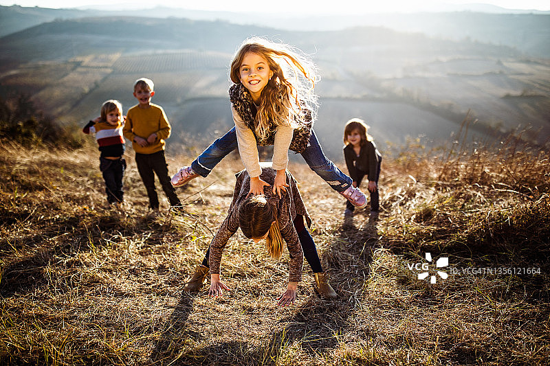 孩子们在秋日里快乐地玩跳山羊游戏图片素材