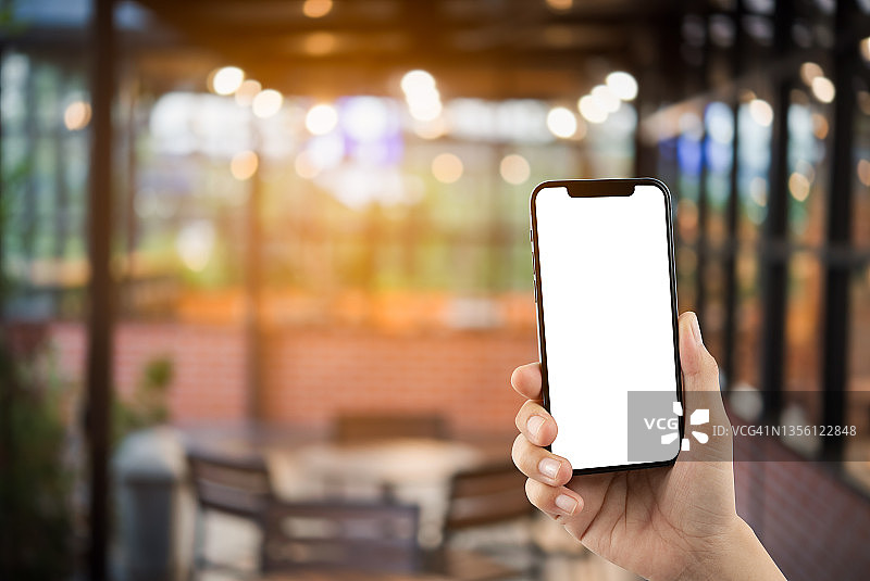 女人展示垂直位置的手机，背景虚化图片素材