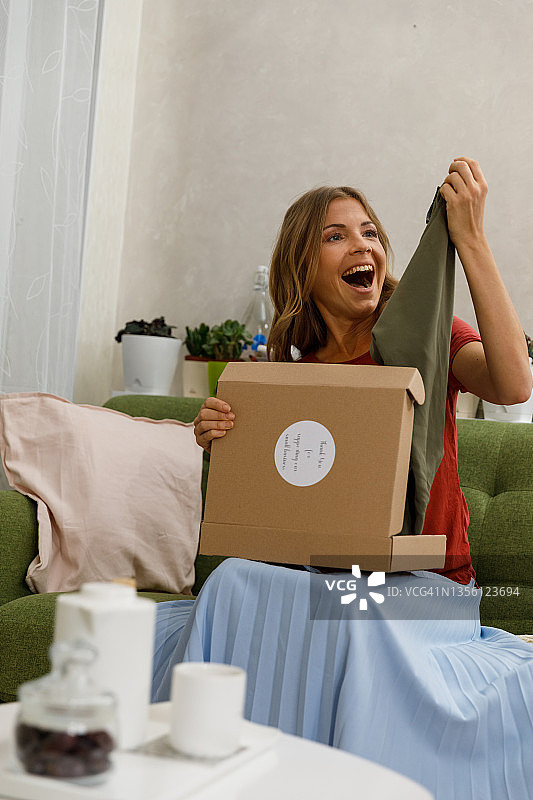 兴奋的女人打开包裹拿着衬衫图片素材