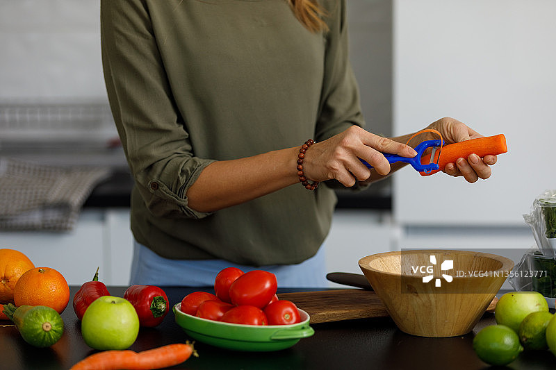 女人削胡萝卜准备健康餐图片素材