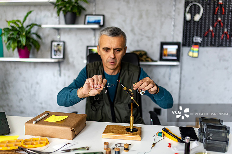 中年男人在他的小作坊里制作飞蝇钓鱼的鱼蝇图片素材