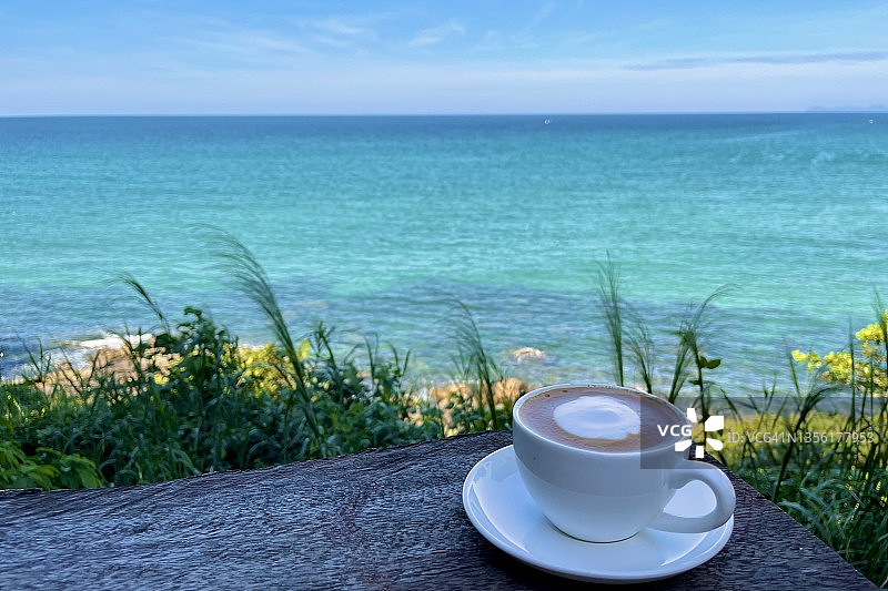 海景阳光下户外木桌上的一杯咖啡图片素材