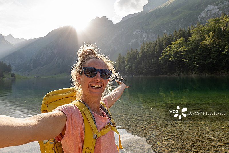 年轻女子在瑞士美丽的湖边徒步自拍，享受大自然和新鲜空气图片素材
