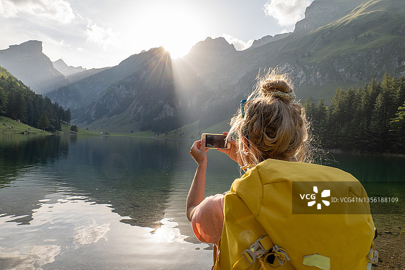 在瑞士拍摄美丽高山湖泊的年轻女子图片素材