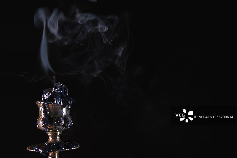 熄灭的蜡烛与烟雾，位于黄铜烛台上，黑色背景，复古风格，神秘氛围图片素材
