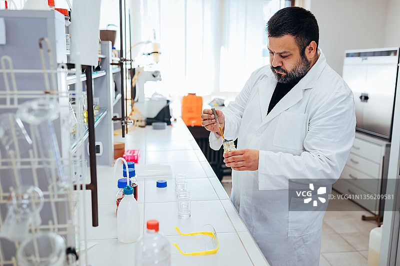 实验室科学实验：严谨的科学家在玻璃器皿中配制化学溶液图片素材