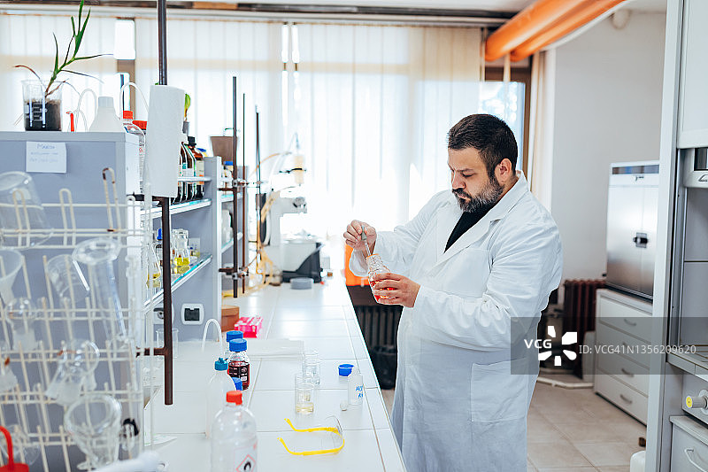 白天，一位身穿白色实验服的化学家正在研究化学品图片素材