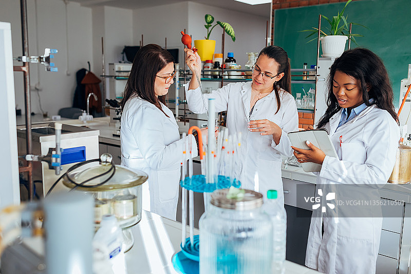 一群年轻科学家在实验室里做实验，多元文化团队测试液体溶液。图片素材