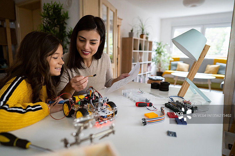 充满爱心的母亲向聪明的女儿讲解如何组装自动驾驶机器人汽车原型图片素材