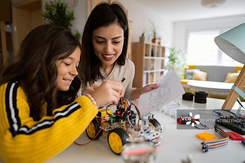 骄傲的母亲帮助女儿组装自动驾驶汽车图片素材