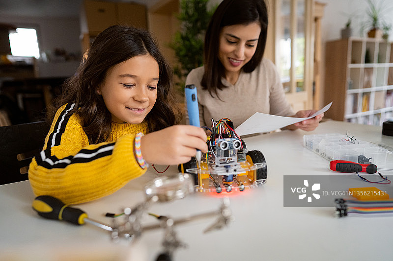 骄傲的母亲帮助聪明的女学生制作自动驾驶机器人汽车原型图片素材