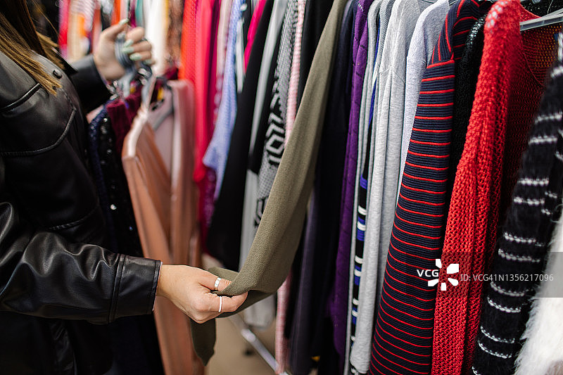 年轻亚洲女孩在二手商店挑选衣服图片素材