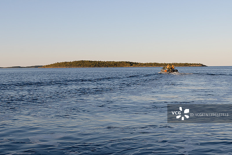 卡累利阿湖泊上的乘船之旅：森林岛屿的日落景观图片素材