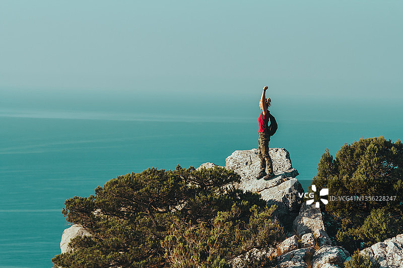 站在悬崖边举起双手的女孩，享受大自然，挑战与勇气图片素材