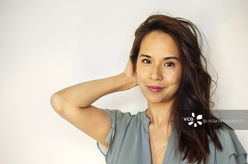 微笑的年轻女人手放在头发上站立图片素材