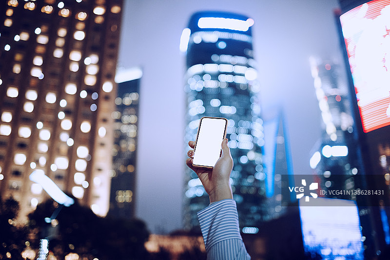 在办公楼下举起手机的女人图片素材