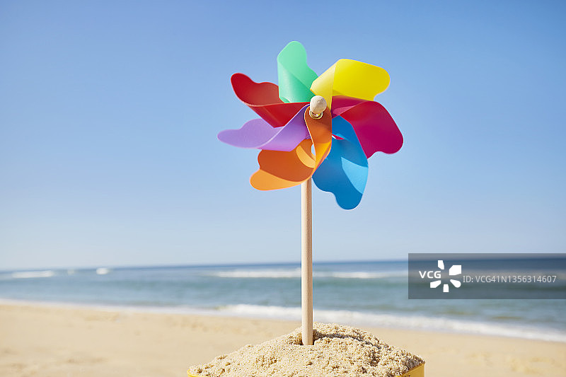 夏季蓝天背景下的海滩彩色风车图片素材