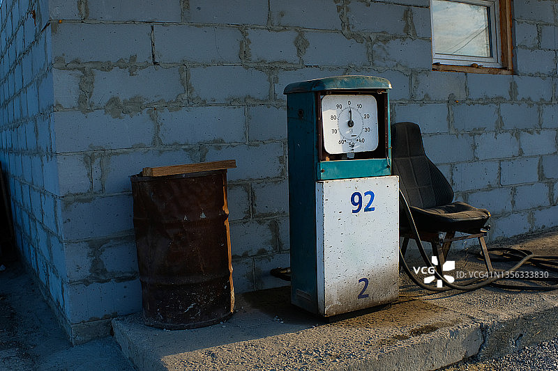 废弃的旧加油站，砖墙旁有汽油泵和破椅子图片素材