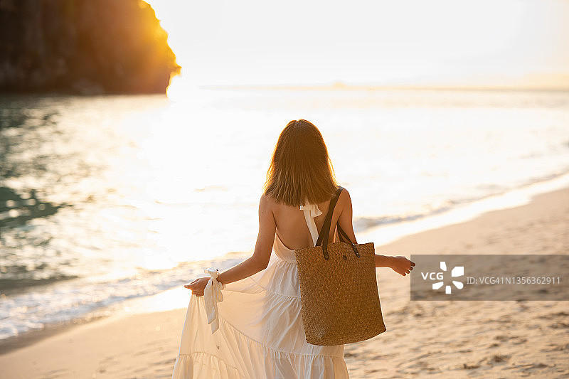 金色黄昏时分，在泰国甲米府莱利东海滩岩石上行走的女孩背影图片素材