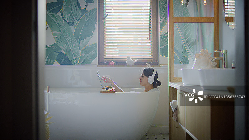 在浴室中进行视频通话：美丽女人在现代浴室放松身心图片素材
