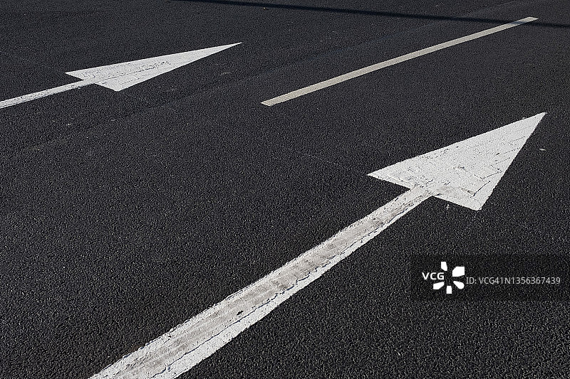 黑色沥青路上的白色箭头和黄色线条图片素材