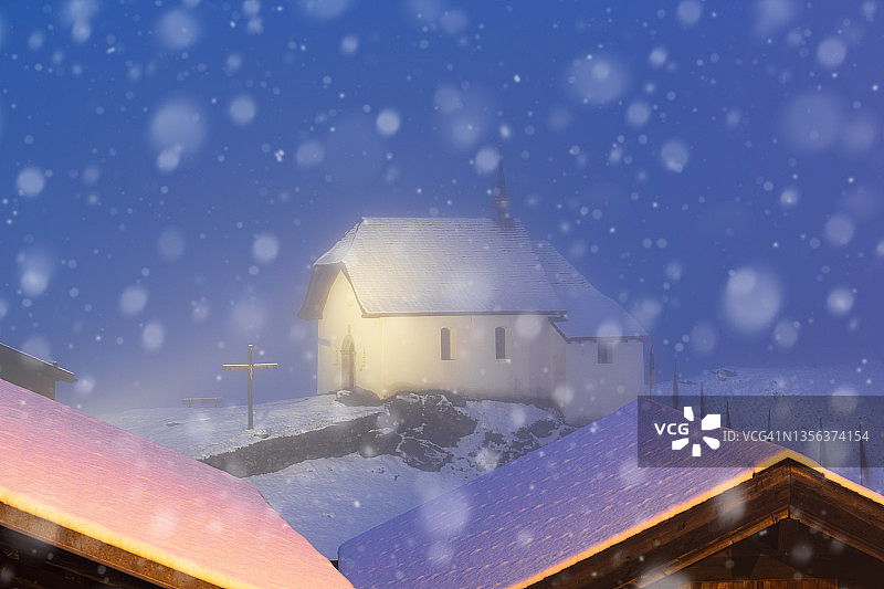 冬日黄昏时分阿尔卑斯山小教堂上的雪花图片素材