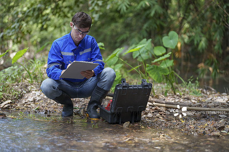 男人使用pH计测量山间河流水质图片素材