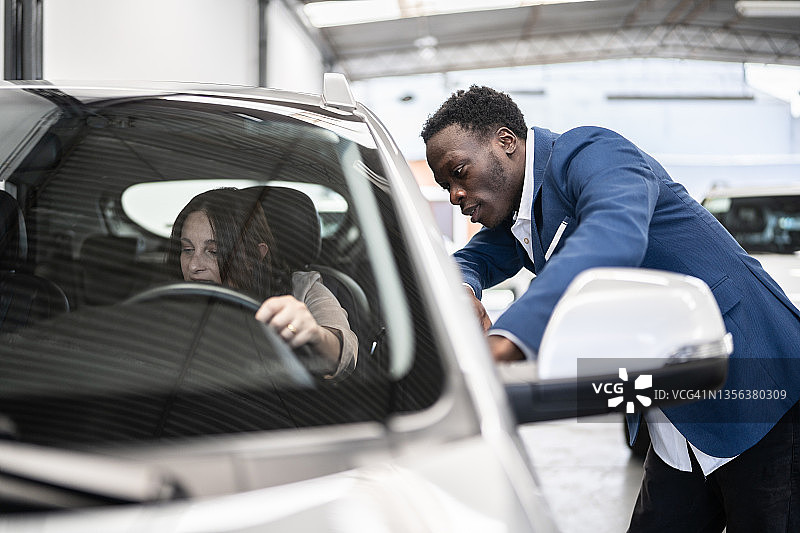 在汽车经销店里向顾客展示汽车的商人图片素材