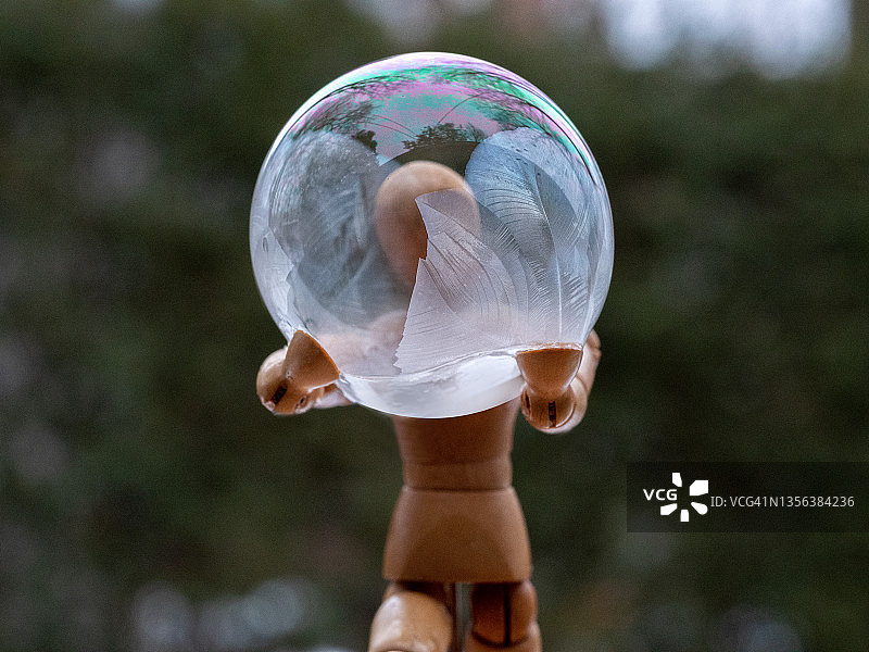 木制模型人偶托起的冰冻肥皂泡图片素材