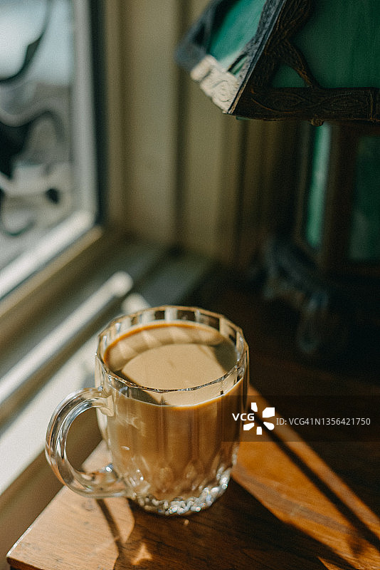 玻璃杯装纯素拿铁咖啡，在木桌上投下阴影图片素材