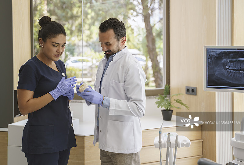 男牙医和女助手在诊所讨论牙科治疗方案图片素材