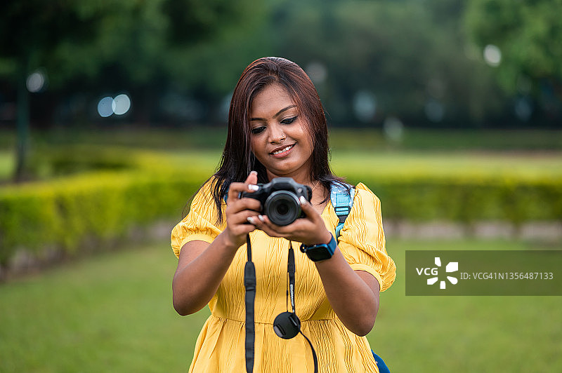 年轻的印度女孩手持相机拍照图片素材