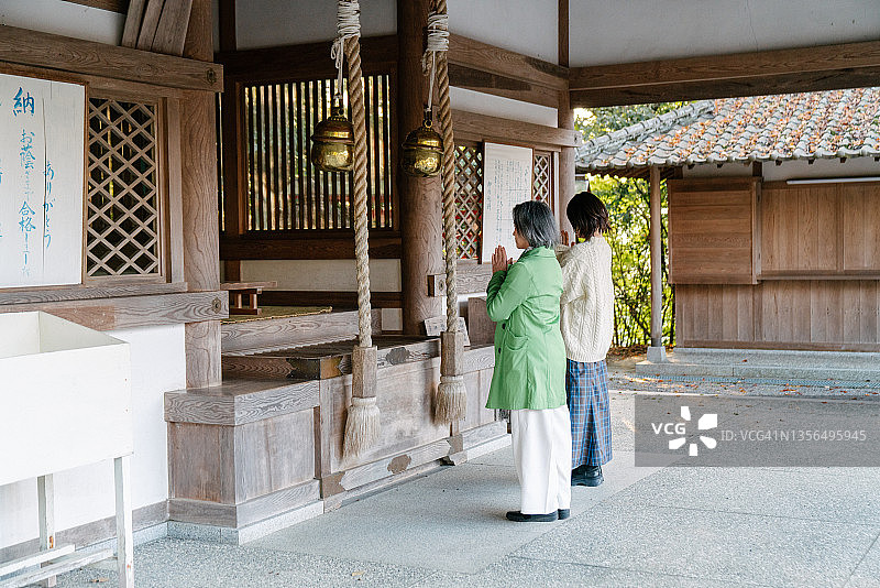 年长女性与成年女儿在寺庙一起祈祷图片素材
