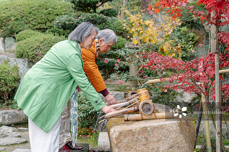 一对年长的夫妇在日本寺庙清洁双手图片素材