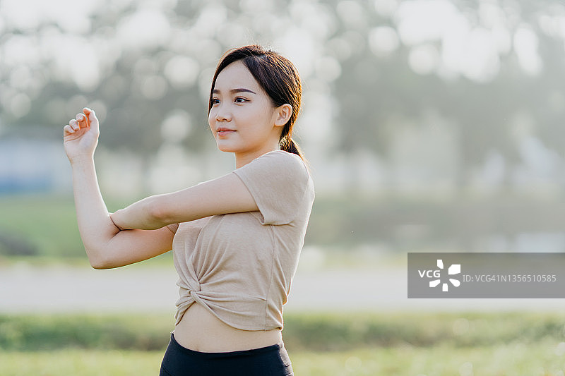 在公园里做伸展运动的快乐年轻亚洲女性图片素材