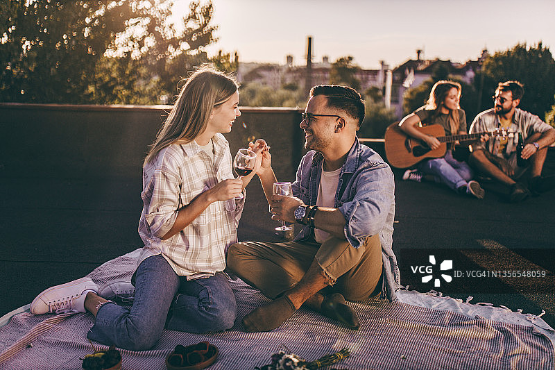 情侣在露台上野餐，一边喝酒一边聊天图片素材