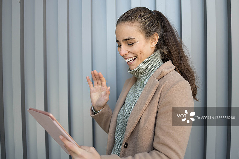 在户外进行视频通话的微笑年轻女人图片素材