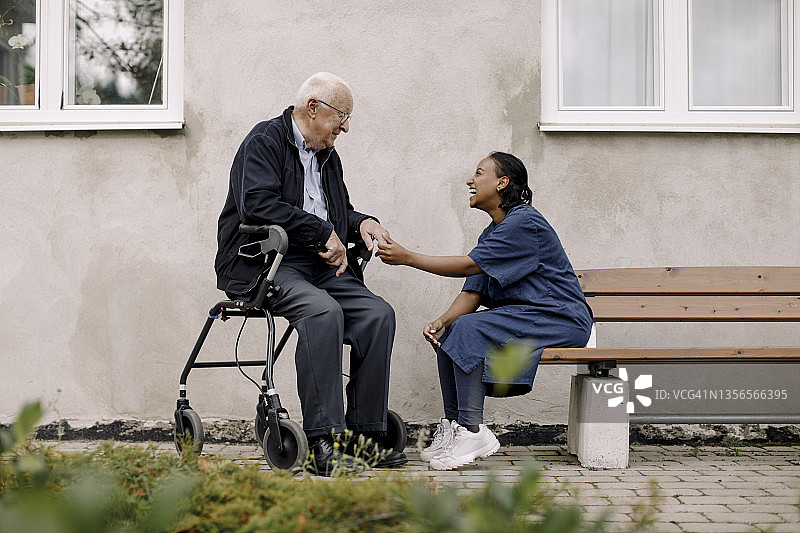 快乐的女医护人员在人行道上与老年男子交谈图片素材