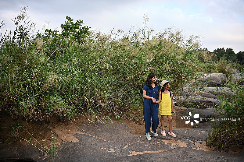 母女站在卡纳塔克邦亨比巨石阵的长草丛中图片素材