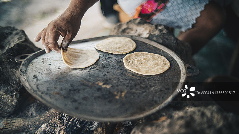 女人在明火上制作新鲜玉米饼的细节图片素材