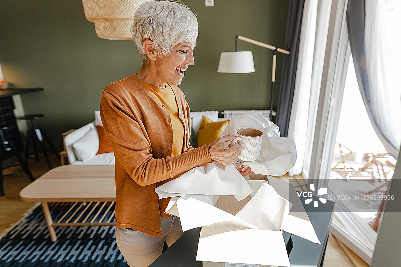年长的女人打开网上订购的包裹图片素材