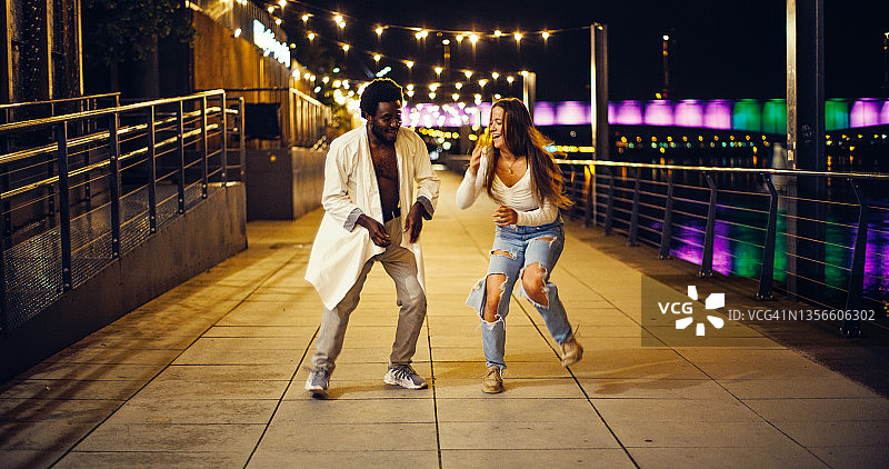 在湿漉漉的城市街道上跳现代快舞的年轻情侣图片素材