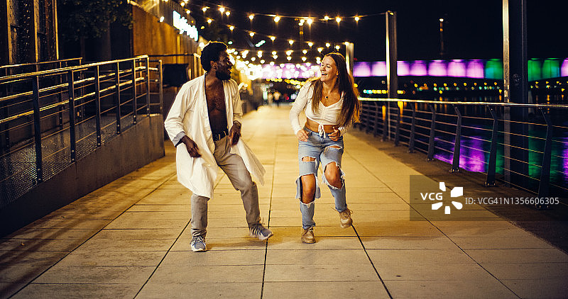 在湿漉漉的城市街道上跳现代快舞的年轻情侣图片素材